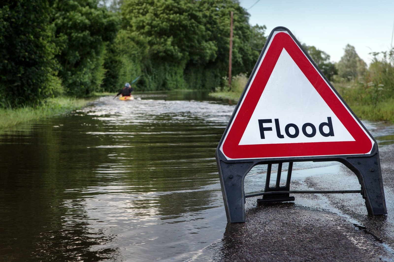 A flood warning sign beside a road covered by water